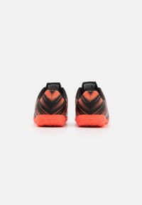 Zapatillas deportivas negras con acentos naranjas vibrantes, con un upper texturizado y una suela de goma con un diseño de agarre estampado.