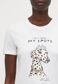 White cotton t-shirt featuring a Dalmatian illustration with a crown and necklace, accompanied by playful text below the graphic.