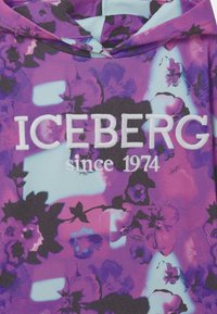 Felpa viola con stampa floreale, caratterizzata da testo bianco "ICEBERG dal 1974". Realizzata in tessuto leggero con una finitura strutturata e cappuccio.