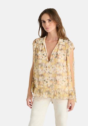 Blusa floral en tejido suave y ligero con escote en V, mangas cortas y dobladillo con volantes. Los colores incluyen patrones en amarillo, rosa y verde.