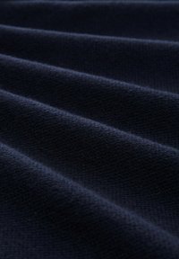 Tissu bleu marine avec une surface douce et texturée, présentant des plis ou des creux diagonaux. Le matériau semble épais et structuré.