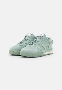 Zapatillas de deporte verde menta que presentan una combinación de texturas suaves y de ante, puntera redondeada, suela de goma gruesa y diseño de cordones.