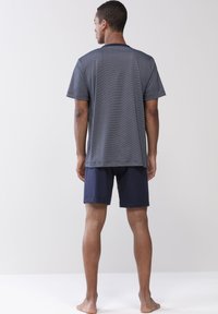 Marinblå randig kortärmad skjorta och enfärgade marinblå shorts. Skjortan har rund hals och avslappnad passform, tillverkad av lättviktsmaterial.