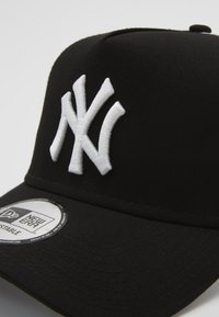 Boné de basebol preto com uma coroa estruturada, apresentando um logo bordado em branco dos New York Yankees e uma alça ajustável com marca.