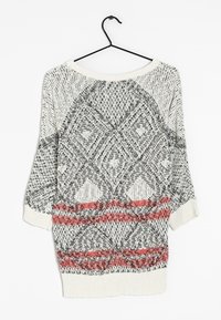 Lekki dzianinowy sweter z geometrycznym wzorem w czerni i bieli z czerwonymi akcentami. Zaprojektowany z szerokim dekoltem i rękawami do połowy przedramienia.