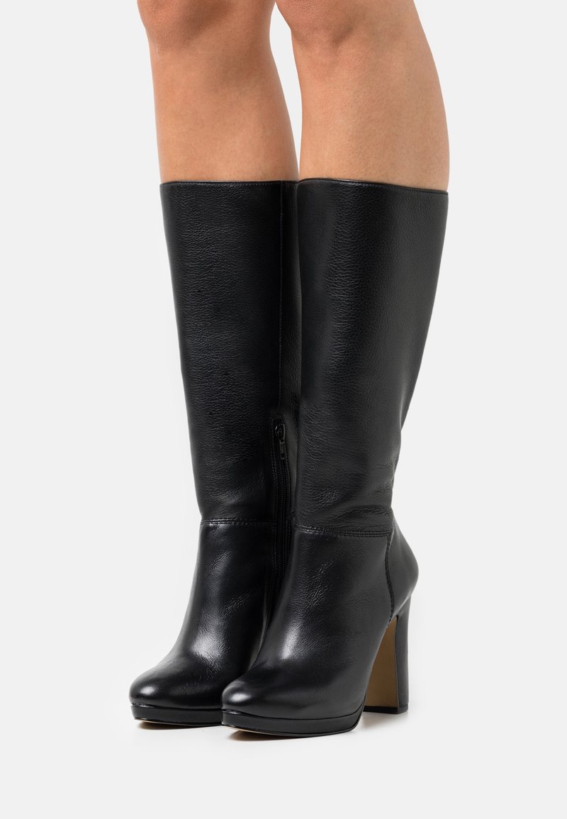 Bottes noires en cuir montant jusqu'au genou avec un talon haut, dotées d'une fermeture éclair latérale, d'une texture lisse et d'un design à bout arrondi.