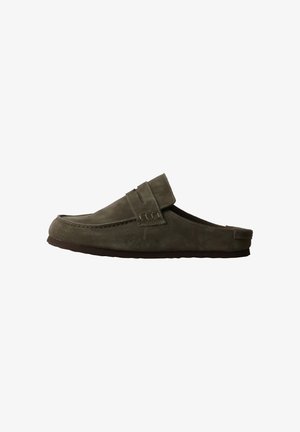 Mocassin en daim vert foncé sans lacets avec une semelle plate et une bride décorative sur le dessus, présenté de profil sur fond blanc.