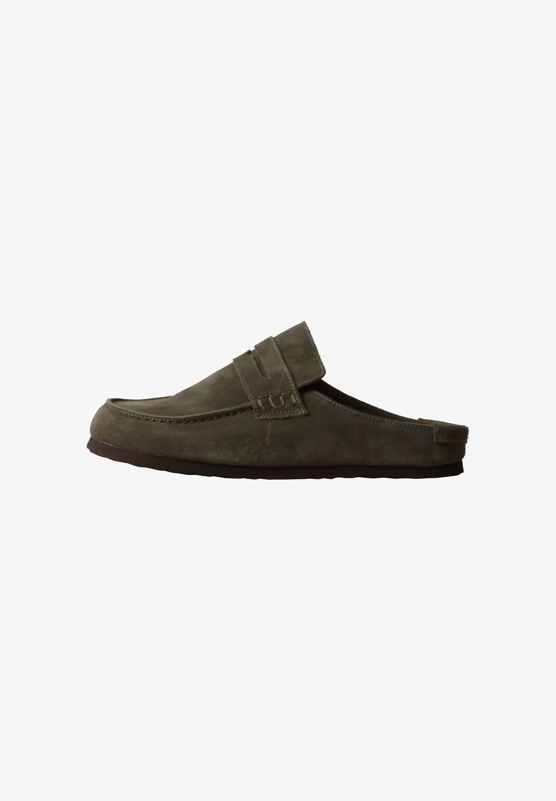 Mocassin en daim vert foncé sans lacets avec une semelle plate et une bride décorative sur le dessus, présenté de profil sur fond blanc.