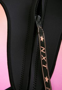 Black wetsuit featuring a pink gradient accent, smooth texture, visible zipper with a branded pull tab, and contrast stitching details.
