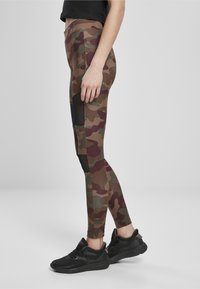 Kaamlusprintidega retuusid pruunis, rohelises ja burgundias koos mustade aktsentpaneelidega. Valmistatud venivast kangast, kombineeritud mustade spordijalatsitega.