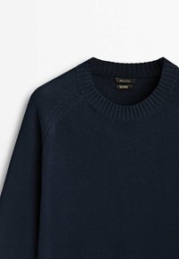 Pull en maille bleu marine avec un col rond côtelé et une texture subtile, orné de surpiqûres au niveau des coutures des épaules.