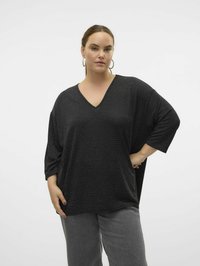 Tunique noire à col en V avec des manches courtes et larges, présentant un léger scintillement et une coupe ample. Associée avec un pantalon gris texturé.