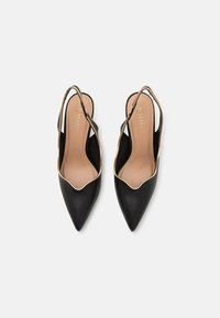 Sorte slingback hæle med spids tå, guldtrim langs kanterne og en glat lædertekstur. Indersiden har en tan-farvet foring.