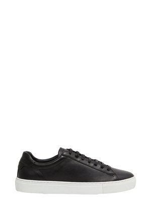 Zwarte lage leren sneaker met zwarte veters en een witte rubberen zool, vanaf de zijkant getoond op een witte achtergrond.