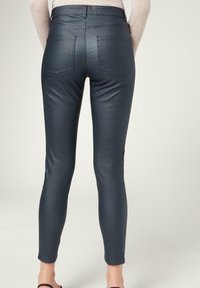 Mörkgrå, elastiska leggings med en slät struktur, två bakfickor och en åtsittande design som smalnar av vid vristerna.