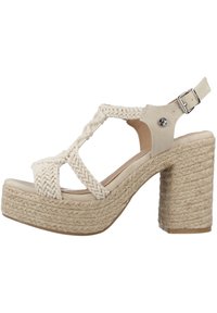 Sandal de color beige claro con tiras de tela trenzada, punta abierta y hebilla en el tobillo; cuenta con una gruesa plataforma de cuerda trenzada y un tacón cuadrado.