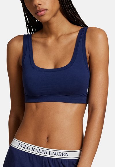 Námořnicky modrý bavlněný bralet s hranatým výstřihem a širokými ramínky; má elastický pás s logem v oblasti pasu. Měkká textura a přiléhavý střih.
