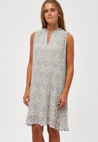 Mouwenloze jurk met bloemenprint in lichte stof. Kenmerkt zich door een keyhole-halslijn met zachte plooien, die net boven de knie valt. Lichte kleuren met subtiele patronen.