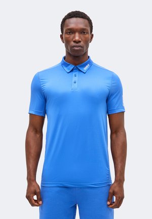 Man draagt een felblauw poloshirt met korte mouwen met de tekst "BORG" op de kraag en linker mouw, staande voor een effen achtergrond.
