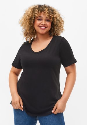 T-shirt noir à col en v avec des manches courtes, fabriqué en tissu doux, présentant une coupe décontractée et un ourlet arrondi, porté avec un jean en denim bleu.