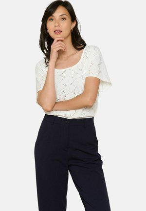 Witte top met korte mouwen en een ronde hals, met een geperforeerd patroon. Gecombineerd met marineblauwe broek met hoge taille.