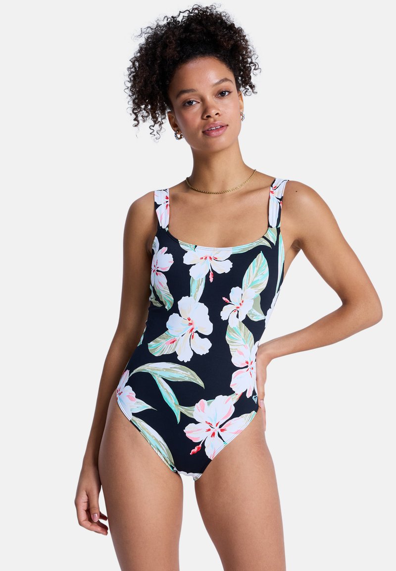 Maillot de bain une pièce à motif floral avec base noire, présentant de grandes fleurs blanches et roses, des feuilles vertes, un décolleté carré et des bretelles larges.