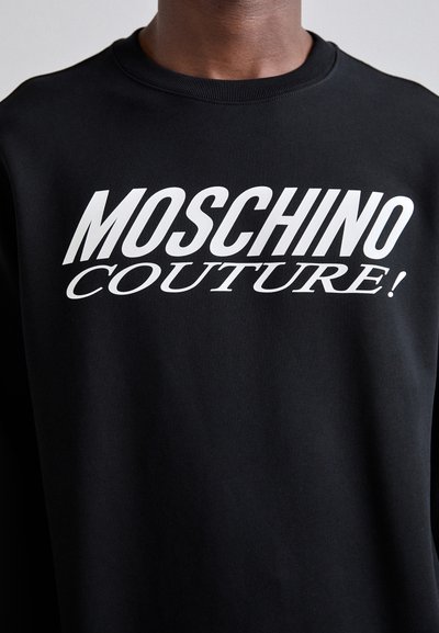 Sweatshirt noir avec le texte blanc en gras "MOSCHINO COUTURE!" sur la poitrine. Fabriqué en tissu doux avec un design classique de col ras du cou.