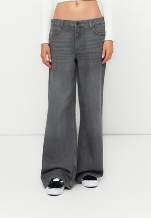 Wide-leg grey denim jeans with a faded finish, featuring five pockets, a button closure, and straight hems. Paired with black sneakers.