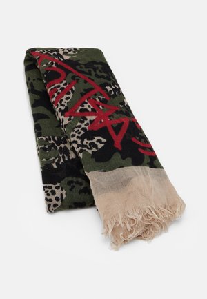Opgevouwen sjaal met groen, beige en zwart camouflagemotief, rood graffiti-achtige tekst en beige franjes aan de randen op een witte achtergrond.