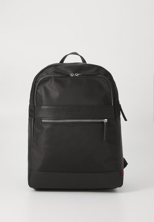 Black fabric backpack with a smooth texture, featuring a top handle, adjustable straps, and a front zip pocket with silver hardware.