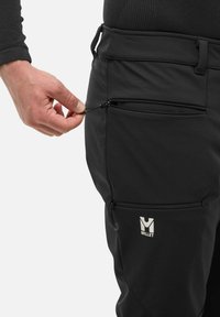Czarne spodnie softshellowe z zamykanymi na zamek bocznymi kieszeniami i logotypem, charakteryzujące się dopasowanym krojem oraz teksturowanym materiałem dla większej trwałości.