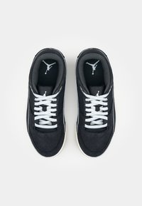 Baskets noires avec un design en mesh et daim, lacets blancs, et un logo Jumpman sur la languette, présentant une forme profilée basse et une semelle en caoutchouc.