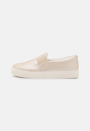 Baskets beige en cuir à enfiler avec panneau élastique, design bas et semelle en caoutchouc blanche plate, présentées en profil latéral sur fond blanc.