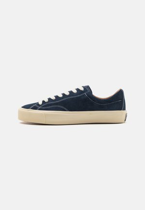 Marine blauwe suède sneakers met witte veters, een beige rubberen zool en contrasterende stiksels. Laag profiel ontwerp met een ronde neus.