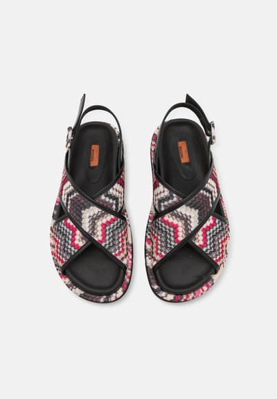 Sandales tissées présentant un motif en zigzag rose, noir et blanc, avec une sangle noire et une boucle, un design à bout ouvert et une semelle rembourrée.