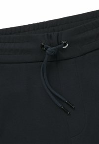 Mörkgrå elastisk midja med snodd. Texturerad tyg med subtilt mönster. Utrustad med metallöglor och eleganta svarta spetsar på snodden.