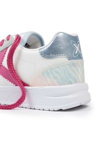 Zapatillas blancas con acentos rosas, talón plateado metálico y panel iridiscente texturizado. Presentan cordones gruesos trenzados rosas y suela blanca.