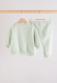 Sweat-shirt vert menthe et pantalon assorti en tissu doux. Le sweat-shirt comporte des manches courtes et des poignets côtelés. Le pantalon est doté d'une ceinture élastique.