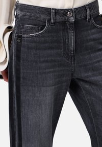 Jeans in denim scuro con vestibilità slim, caratterizzati da una leggera sfumatura, strisce laterali e design tradizionale delle tasche. Bottone in metallo in vita.