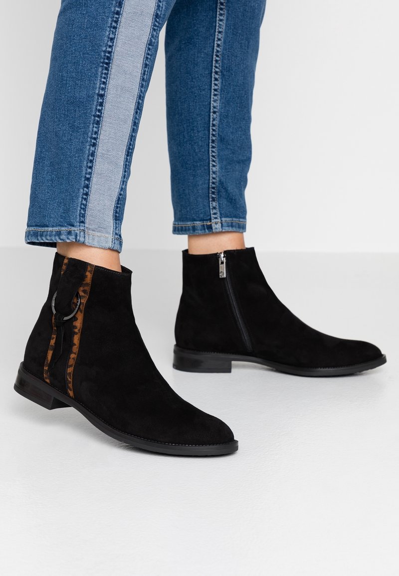 Bottes cheville en daim noir avec une fermeture éclair latérale et un accent en imprimé léopard. Design à talon bas avec une semelle en caoutchouc lisse.
