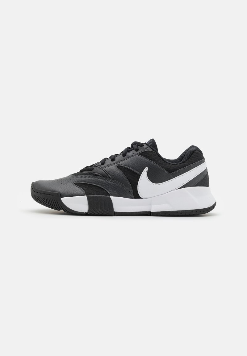 Crne atletske tenisice od sintetičkih i mrežastih materijala, s bijelim Nike logotipom, teksturiranim vrhom cipela i gumenim potplatom za prianjanje.