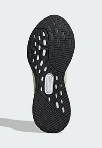 Suela de zapato de goma negra con patrón de tracción texturizado, que presenta acentos blancos y recortes para mayor flexibilidad. El diseño es curvado y funcional.