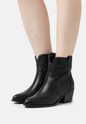 Svarta cowboy-stövlar av mjukt läder med spetsiga tår, kort skaft och sydda detaljer på sidorna. Blockklack.