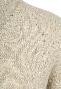 Lichtbeige gebreide trui met een gestructureerd patroon met vlekjes bruin en blauw, een ronde halslijn en geribbelde accenten.