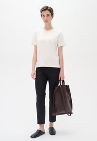 Light cream short-sleeve top, black slim-fit pants, black flat shoes, and a dark brown leather tote bag with short handles. Simple design.