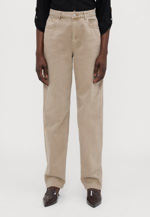 Beige leveled trousers made of denim, featuring a high waist, five-pocket design, subtle stitching, and a smooth texture.