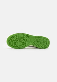 Nike-sneaker sula i grön gummi, med cirkulära och linjära mönster. Slät yta med präglad logotypdetalj.