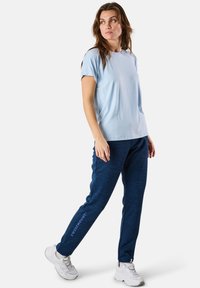 Ljust blå kortärmad skjorta kombinerad med marinblå strukturerade leggings med en logotyp, designad för komfort och avslappnad användning.