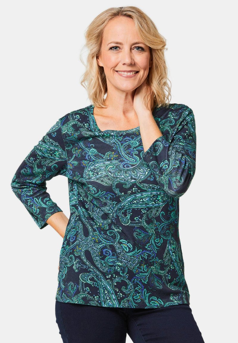 Langarm-Bluse in dunklem Marineblau mit komplexem grünen Paisley-Muster. Weicher, dehnbarer Stoff mit einem U-Boot-Ausschnitt.