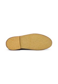 Suela de un zapato con una superficie amarilla texturada y una forma curva, sobre un fondo blanco liso.